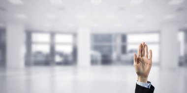 İş kadınının eli ekranda kapalı ve arka planda avuç içi ve ofis