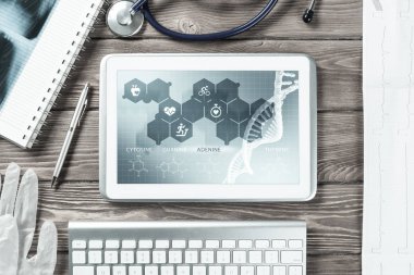 Beyaz tablet bilgisayar ve doktor aletleri ahşap masada.