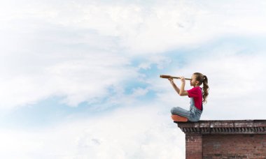 Evin çatısında oturan ve dürbüne bakan tatlı bir kız.