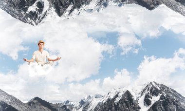 Genç adam gözleri koruma kapalı ve seyir bulut doğa dünyalar arasında havada meditasyon sırasında konsantre.