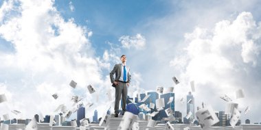 Kendine güvenen işadamı belgeleri kağıtları Clear sky ile arka plan üzerinde uçan arasında yığını üzerinde takım elbise ayakta. Karışık teknik.