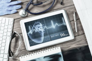 Beyaz tablet bilgisayar ve doktor aletleri ahşap masada.