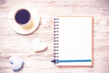 Kahve fincanı not defteri kalem ve ahşap yüzeyde iki kalp