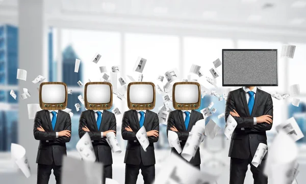 Businessmen in suits with old TV instead of their heads keeping arms crossed while standing in a row and one at the head with TV inside office building.