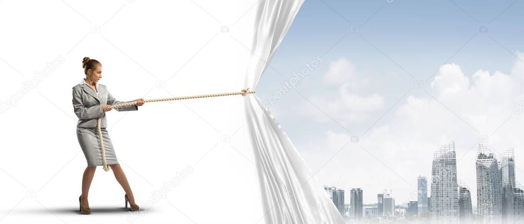 Young woman opening white curtain and presenting modern city landscape