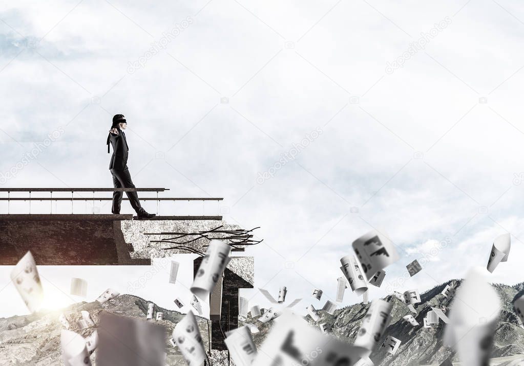 Businessman walking blindfolded among flying papers on concrete bridge with huge gap as symbol of hidden threats and risks. Skyscape and nature view on background. 3D rendering.