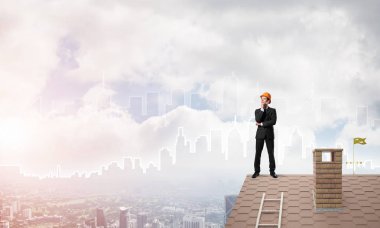 Mühendis adam çatıda dikiliyor ve başka tarafa bakıyor. Karışık ortam