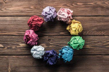 Yeni fikirlerin arama aracı olarak daire ahşap masa üzerinde birden çok renkli crampled kağıt topu kümesi yerleştirilir.