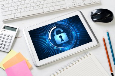 Ofis eşyalarıyla iş yeri ve ekranda asma kilit simgesi olan tablet