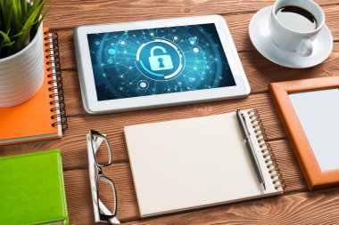 Ofis eşyalarıyla iş yeri ve ekranda asma kilit simgeleri olan tablet