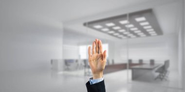 İş kadınının eli ekranda kapalı ve arka planda avuç içi ve ofis