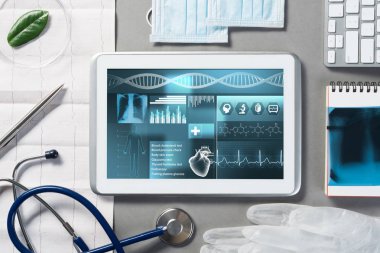 Gri yüzeyde beyaz tablet ve doktor araçları