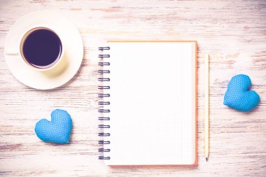Kahve fincanı not defteri kalem ve ahşap yüzeyde iki kalp