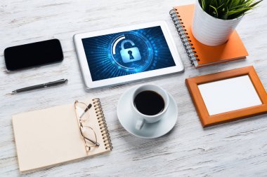 Ofis eşyalarıyla iş yeri ve ekranda asma kilit simgeleri olan tablet