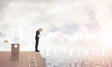 Takım elbiseli genç işadamı ve çatıda kask var. Karışık ortam