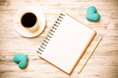 Kahve fincanı not defteri kalem ve ahşap yüzeyde iki kalp
