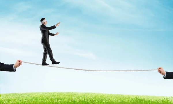 Business concept of risk support and assistance with man balancing on rope — Stock Photo, Image