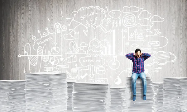 Attractive man sitting on pile of paper documents. — Stock Photo, Image