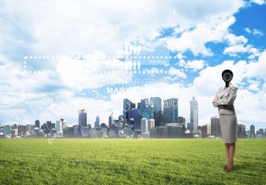 Modern şehir manzarasına karşı yeşil çimlerin üzerinde duran kamera kafalı kadın.