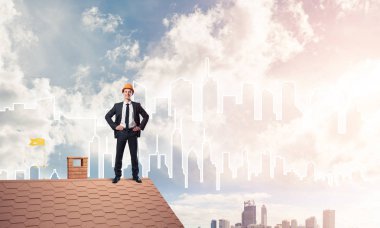 Mühendis adam çatıda dikiliyor ve başka tarafa bakıyor. Karışık ortam