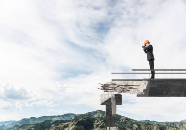 Genç takım elbiseli mühendis ve dürbün ile gökyüzü arka plan üzerinde kırık köprü üzerinde dururken seyir kask. 3D render.