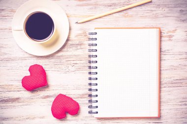 Kahve fincanı not defteri kalem ve ahşap yüzeyde iki kırmızı kalp