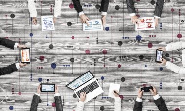 Ellerinde cihazlar bulunan bir grup insan, iletişim ve ağın sembolü olarak birlikte çalışıyor.