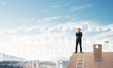 Mühendis adam çatıda dikiliyor ve başka tarafa bakıyor. Karışık ortam