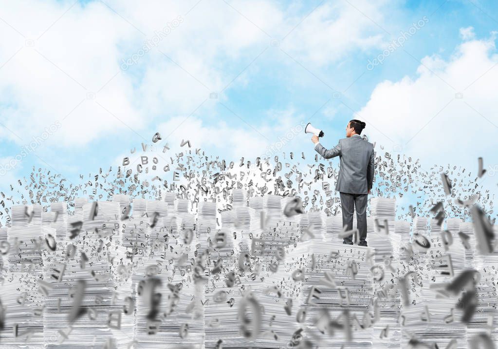 Businessman in suit standing on pile of documents among flying letters with speaker in hand with cloudly skyscape on background. Mixed media.
