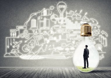 Boş beton odada ampulün içindeki iş adamı ve duvardaki çizimler