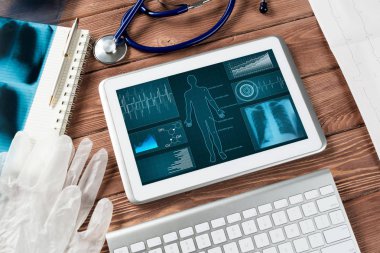 Beyaz tablet bilgisayar ve doktor aletleri ahşap masada.