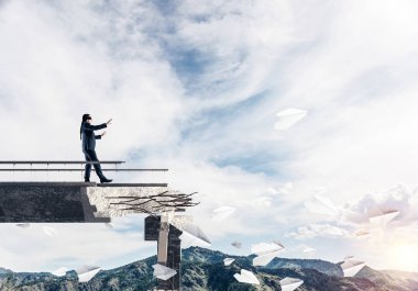 Gizli tehditlerin ve risklerin sembolü olarak beton köprüde gözü kapalı yürüyen bir iş adamı. Arka planda gökyüzü ve doğa manzarası. 3B görüntüleme.