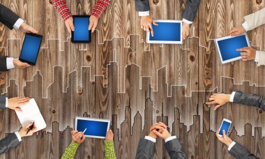 Ellerinde cihazlar bulunan bir grup insan, iletişim ve ağın sembolü olarak birlikte çalışıyor.