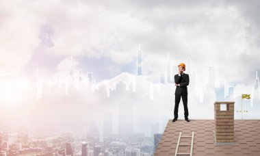 Mühendis adam çatıda dikiliyor ve başka tarafa bakıyor. Karışık ortam