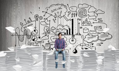 Kağıt belgeleri yığını üzerinde oturan çekici adam.