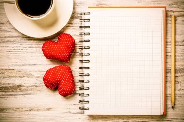 Kahve fincanı not defteri kalem ve ahşap yüzeyde iki kırmızı kalp