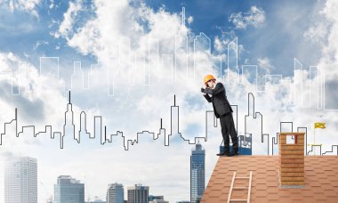 Çatıda duran ve dürbüne bakan mühendis. Karışık ortam