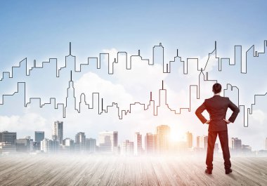 İşadamı arkasını dönüp modern iş merkezinin siluetine bakıyor.