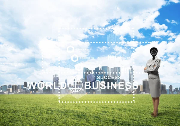 Camera headed woman standing on green grass against modern cityscape — Stock Photo, Image