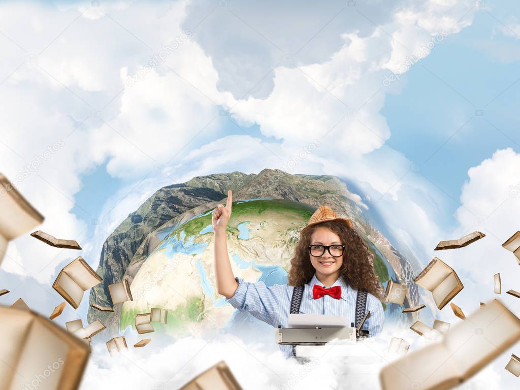 Beautiful woman writer in hat and eyeglasses pointing up while using typing machine at the table with flying books and Earth globe among cloudy skyscape on background. Elements of this image furnished by NASA