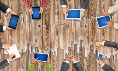 Ellerinde cihazlar bulunan bir grup insan, iletişim ve ağın sembolü olarak birlikte çalışıyor.