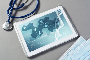 Gri yüzeyde beyaz tablet ve doktor araçları