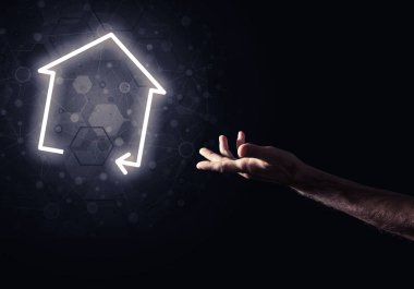 İnsanın eli parlayan ev simgesi ya da sembolüyle dokunuyor