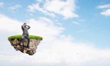 Yeşil Adası'nda oturan ve elleriyle kulaklarını kapatarak sinirli işadamı