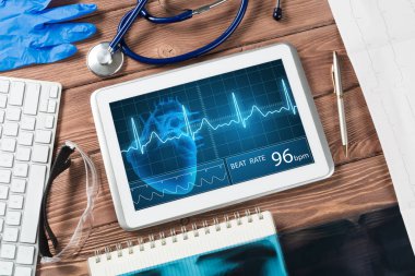 Beyaz tablet bilgisayar ve doktor aletleri ahşap masada.