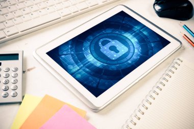 Ofis eşyalarıyla iş yeri ve ekranda asma kilit simgesi olan tablet