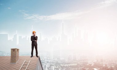 Takım elbiseli genç işadamı ve çatıda kask var. Karışık ortam