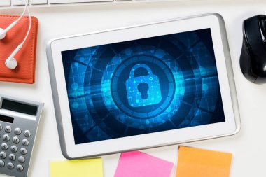 Ofis eşyalarıyla iş yeri ve ekranda asma kilit simgesi olan tablet