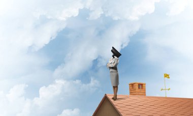 Evin çatısında baş durmak yerine kamerayla zum yapan yüzsüz iş kadını.