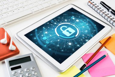 Ofis eşyalarıyla iş yeri ve ekranda asma kilit simgesi olan tablet